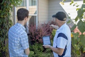 exterior home inspection with client, pointing out landscaping too close to home